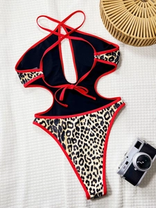Costume intero leopardato con bordi rossi e fotocamera vintage su sfondo bianco