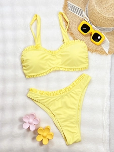 Bikini deux pièces jaune vif avec détails à volants sur fond blanc de style estival