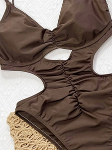 Dark brown one-piece swimsuit with waist cut-outs and ruched detailing on white texture