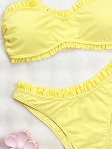 Ensemble bikini deux pièces jaune vif avec volants sur fond blanc doux