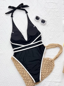 Minimalist black one-piece swimsuit with white trim and crisscross waist straps