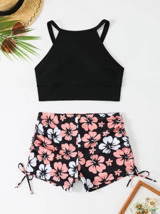 Haut de maillot noir et bas shorty floral avec cordons latéraux sur fond de plage d'été
