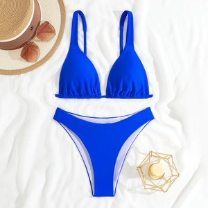 Flat lay of royal blue bikini with ruched triangle top and high cut bottoms on white linen
