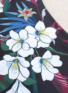Close-up of tropical floral print on navy one-piece swimsuit with white lily pattern