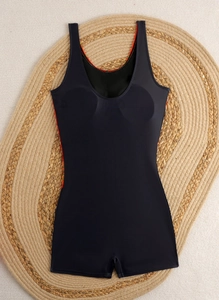 Detail of black one-piece swimsuit with racerback straps on a woven straw mat