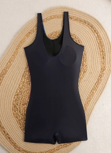 Detailed flat lay of black one-piece swimsuit with built-in padding on straw mat