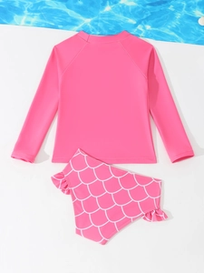 Detail van roze meisjeszwemkleding met lange mouwen en een witte visschubbenprint