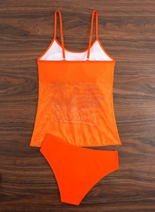 Detail of bright orange two-piece swimsuit with mesh tankini top and high-waisted bottoms