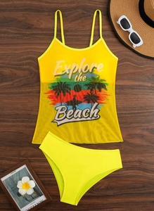 Flat lay detail of yellow tankini set with tropical print on a wooden background