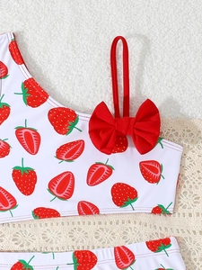 Detail of strawberry print swimsuit featuring a large red 3D bow on shoulder strap