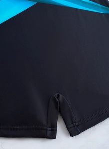 Detailed macro view of black athletic swim shorts with blue side panel and hem slit detail