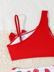 Close-up of red strawberry print girl's bikini with adjustable straps and bow detail