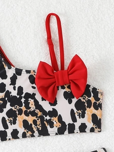 Close-up of girls bikini top with cow print pattern and a large red bow detail