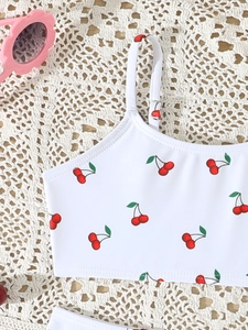 Detail van een wit bikini-topje voor meisjes met kersenprint en dunne bandjes