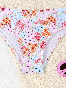 Detail van bikini-broekje voor meisjes met bloemenprint en roze zonnebril op kant