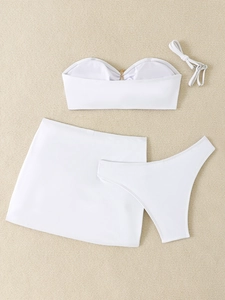 Flat lay of white three-piece bikini set including strapless top with V-metal detail and skirt