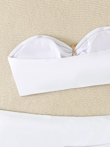 Detail of white bikini top with a golden V-shaped metal hardware on woven texture