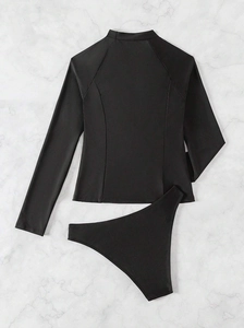 Dettaglio costume da bagno nero a due pezzi con maniche lunghe e slip a vita alta su marmo