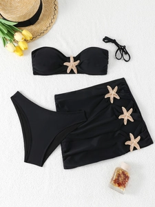 Flat lay of black three-piece bikini set with metallic starfish detail and sarong skirt