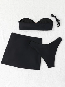 Flat lay of black 3-piece bikini set with bandeau top, high-cut briefs and matching mini skirt