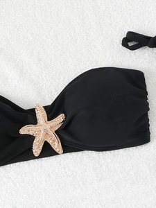 Detailed view of black bikini top featuring a gold starfish charm with rhinestones