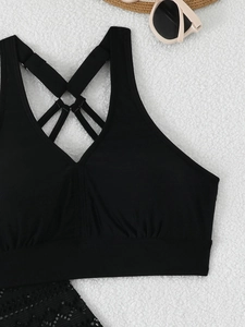 Detail von schwarzem Tankini-Oberteil mit gekreuzten Trägern und Falten-Saum auf Plüsch