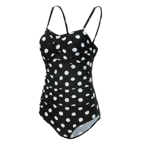 Detailed view of black polka dot swimsuit featuring adjustable straps and gathered tummy control