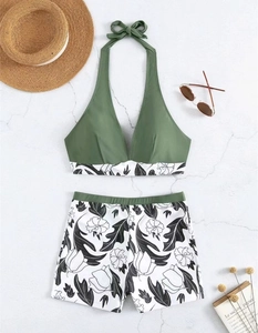 Flat lay of army green halter bikini top and floral high waisted shorts on marble background
