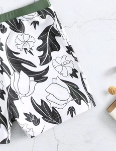 Detailed macro view of tropical floral print on white men's swim trunks with green waistband