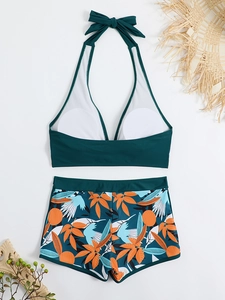 Dettaglio flat lay del top bikini verde allacciato al collo e pantaloncini tropicali