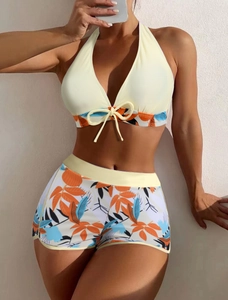 Dettaglio del top bikini giallo allacciato al collo con pantaloncini floreali tropicali