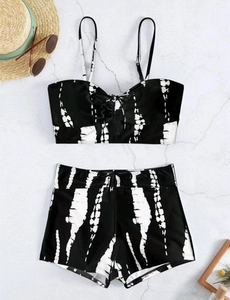 Flat lay of black and white tie-dye bikini set with high waist swim shorts and straw hat
