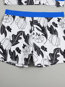 High-waisted bikini bottoms with white floral print and bright blue contrast waistband