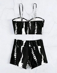 Flat lay of black two-piece tankini swimsuit with white abstract tie-dye patterns