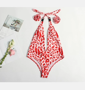 Flat lay of a white one-piece swimsuit with red leopard print and deep V-neckline