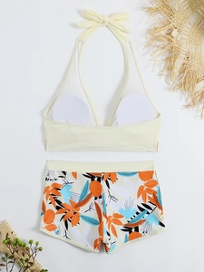 Flat lay di top bikini giallo a girocollo con fiocco e pantaloncini a stampa tropicale