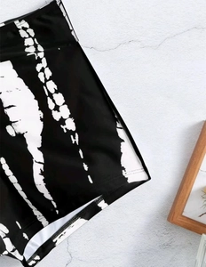 Detail of high-waisted black and white tie-dye bikini bottoms with elastic fabric texture