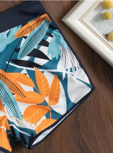 Dettaglio ravvicinato di pantaloncini bikini con stampa tropicale ed elastico blu