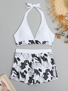 Flat lay of high-waist bikini with floral shorts and halter top on resort background