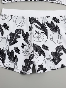 Detail of high-waisted bikini bottoms with black floral print and wide white waistband