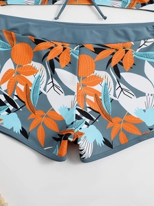 Dettaglio dei pantaloncini da nuoto blu a vita alta con motivi di foglie tropicali