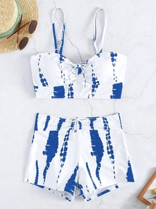 Flat lay of blue tie-dye bikini set with drawstring details and beach accessories
