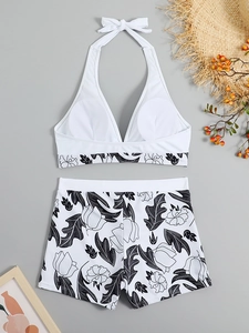 Flat lay of white halter bikini top and floral high-waisted shorts with summer props