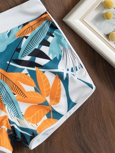 Dettaglio degli shorts bikini con stampa a foglie tropicali e fascia elastica bianca