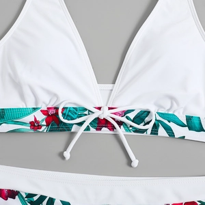 Dettaglio del top bikini bianco con scollo a V profondo e stampa floreale tropicale