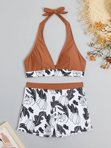 Flat lay of rust-red halter bikini top and floral high-waisted shorts on summer background
