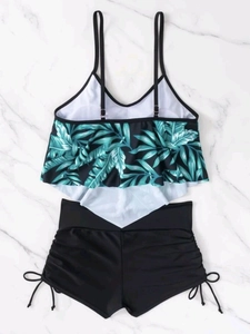 Detail showing tropical palm leaf print top with ruffled hem and black high waist bikini bottom