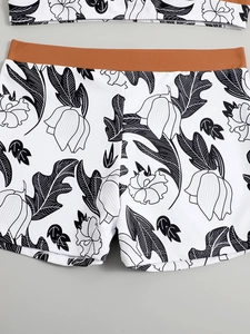 Close-up of high-waist bikini bottoms with black and white tropical floral print and brown band