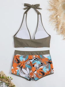 Top bikini a fascia verde oliva e pantaloncini con stampa tropicale con cappello di paglia