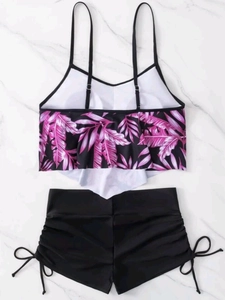 Detail of high waisted bikini bottoms with side drawstrings and ruffled tropical top